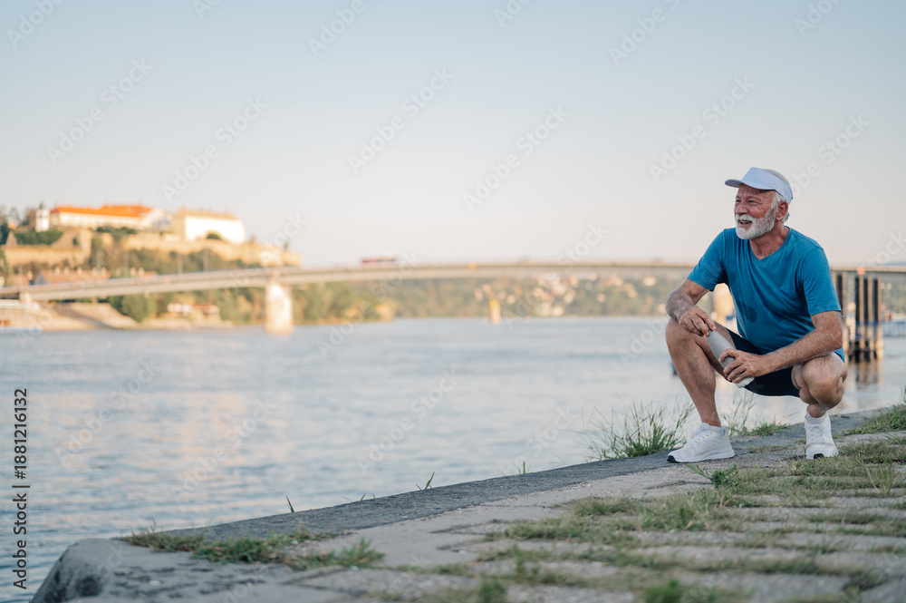 Fototapeta premium Senior athlete resting by river after workout, enjoying fitness and active lifestyle