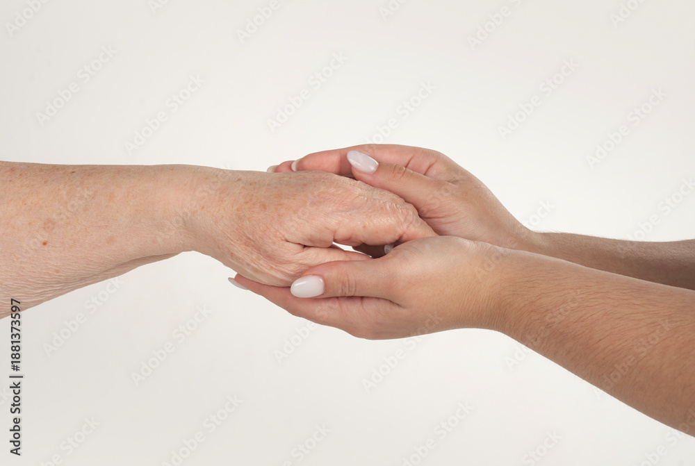 Fototapeta premium Woman holding grandmothers hand. Care and help concept. Young hand holding an old hands. Elderly woman hands close up. Hand help bridges age. Hand help connects old young.