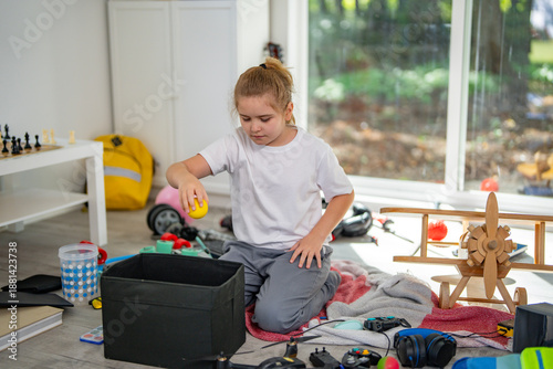 Fotografija Child cleaning messy playroom at home