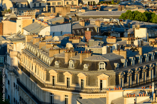 Foto Elegant Parisian Haussmann buildings with ornate zinc rooftops and rows of brick chimneys, bathed in golden sunlight