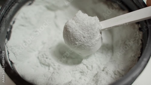 Taking a scoop of creatine from a jar, close-up
