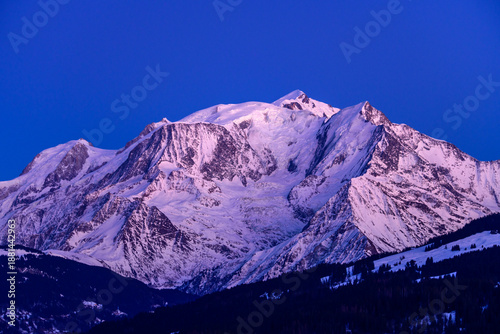 The snow-capped Mont Blanc massif is bathed in vivid pink and blue twilight, with intricate glacier lines and sharp alpine ridges standing out against a deep sky.