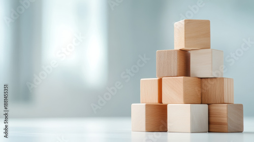 Wooden blocks stacked in pyramid shape on white surface with soft natural light creating calm and balanced atmosphere