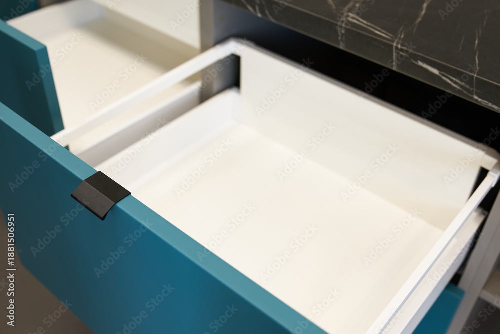 Fototapeta premium Open drawers of a modern kitchen set with blue fronts.