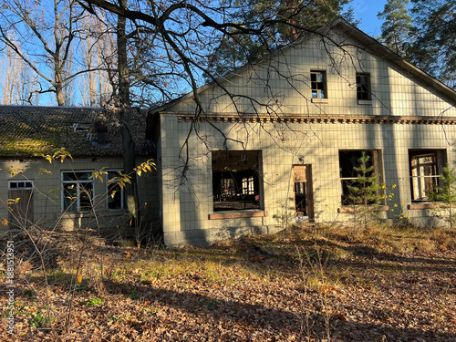 Abandoned house stands quietly in a forest clearing, its broken windows revealing decay and silence. Ukraine, Bucha region