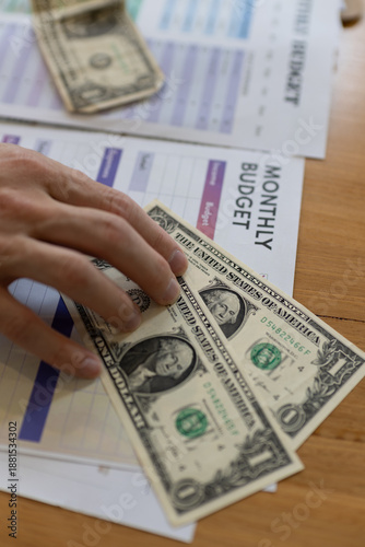 Εκτύπωση καμβά Hand placing US dollar cash on monthly budget worksheet on wooden desk