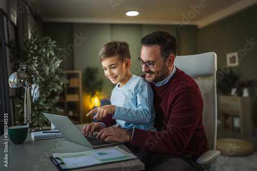 Foto Father and son happily working together on laptop at home
