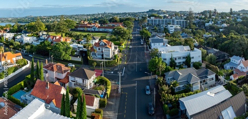 Aerial view of a residential street in Parnell, Auckland, New Zealand. The photo shows houses, trees, and cars on the road. The image captures the urban landscape of Auckland.