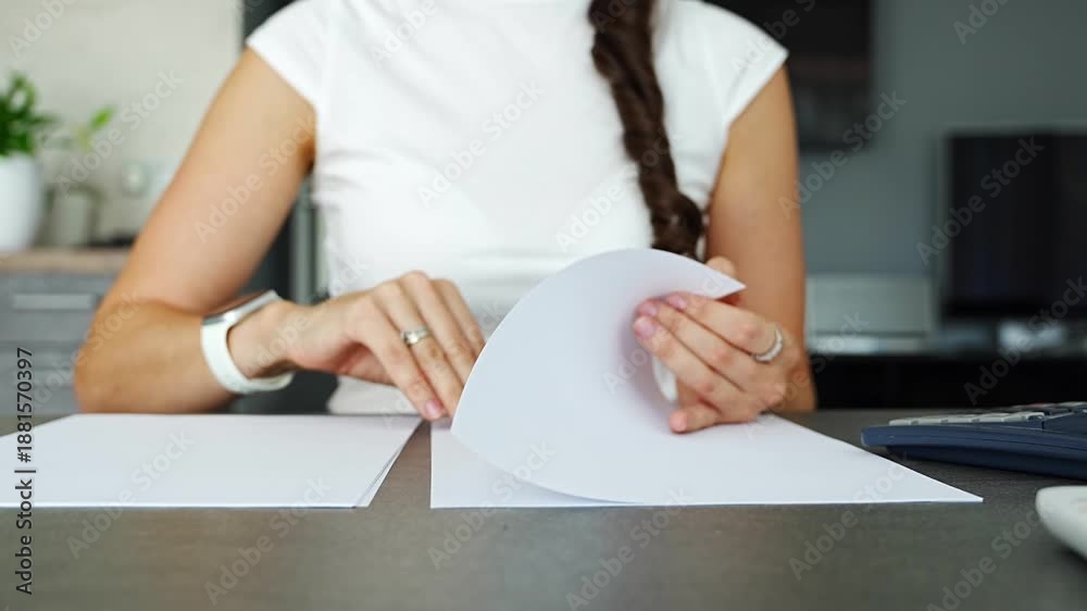 Close up of woman hands reviewing and flipping through paper documents ...