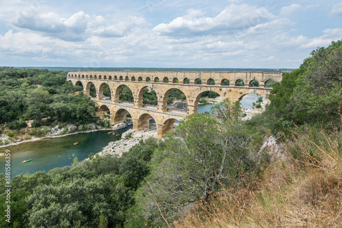Pont du Gard, an ancient Roman aqueduct in southern France, captured in bright sunlight against a clear blue sky.