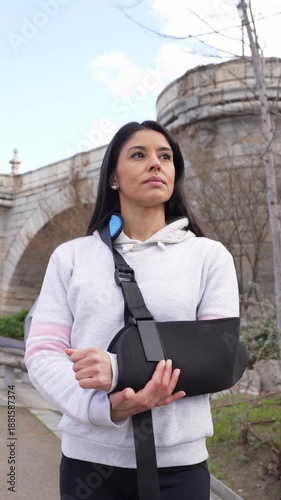 Woman with a broken arm in a sling taking a rehabilitative walk outdoors in a city park