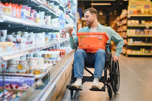 Obraz na płótnie Customer in wheelchair choosing groceries in supermarket