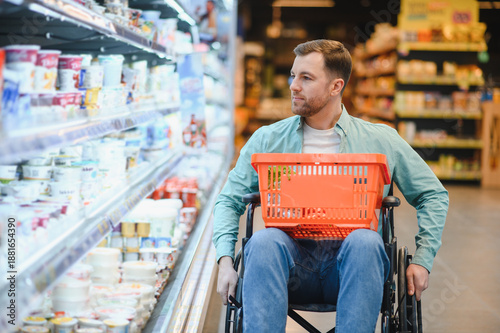 Fotografía Customer in wheelchair choosing groceries in supermarket