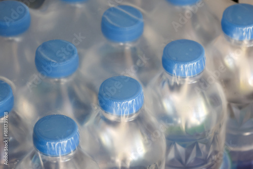 Foto Pack of clear plastic water bottle with blue cap shrink wrapped reflecting fresh