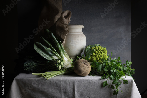 Composizione vegetale con vaso in marmo e ortaggi freschi su tavolo rustico
