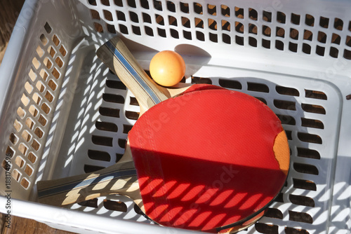 Obraz na płótnie Bright red ping pong paddle with wooden handle lying next to orange ball inside