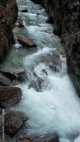 A beautiful vertical video showing a turquoise mountain river flowing through a rocky canyon surrounded by golden autumn trees and majestic peaks.