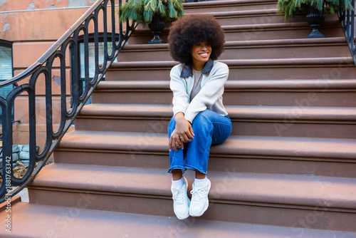 Bild auf Leinwand Smiling woman sitting on brownstone steps in harlem new york city