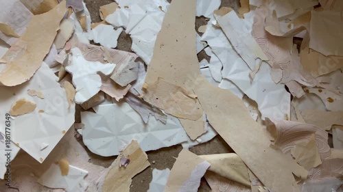 Torn wallpaper on the floor as a background, harsh shadows, renovation process