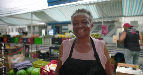 African American elderly woman portrait at outdoor produce market smiling gently and reflecting pride familiarity and human presence in everyday local street commerce