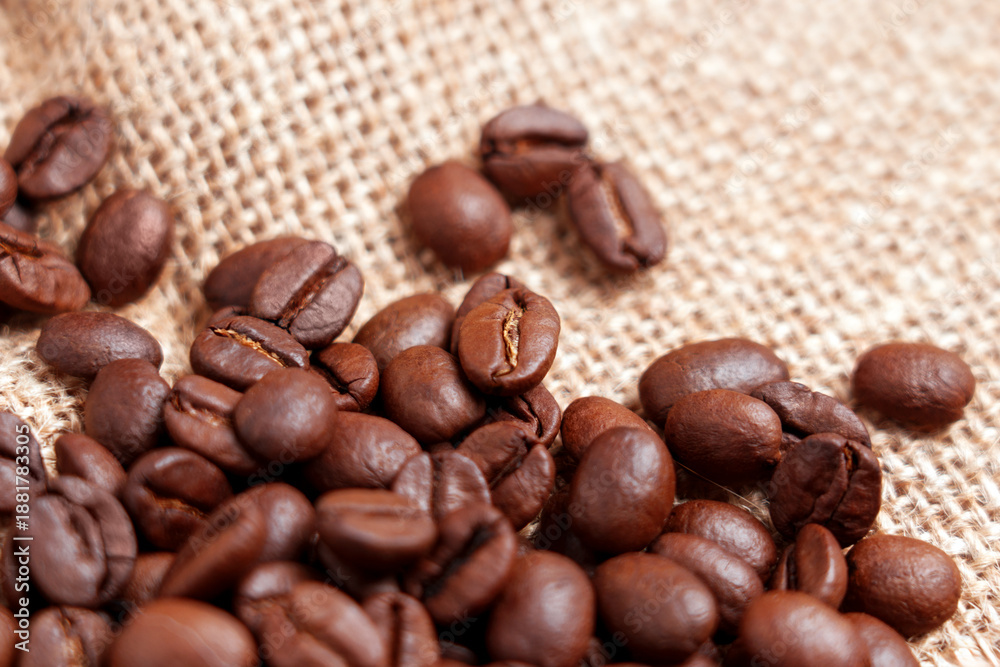 Obraz premium Close-up of freshly roasted coffee beans on rough burlap. Rustic View