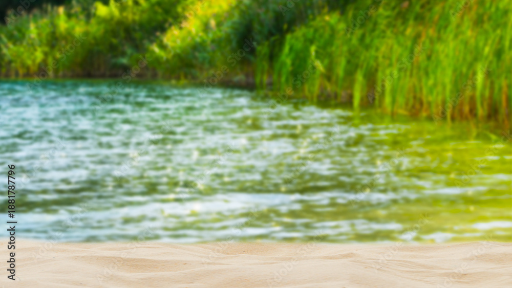 Fototapeta premium idyllic sand beach and reeds lakeside in sommertime, blurred background with copy space in foreground for product presentations, sunny backdrop for beauty spa, vacation, travel and relaxation