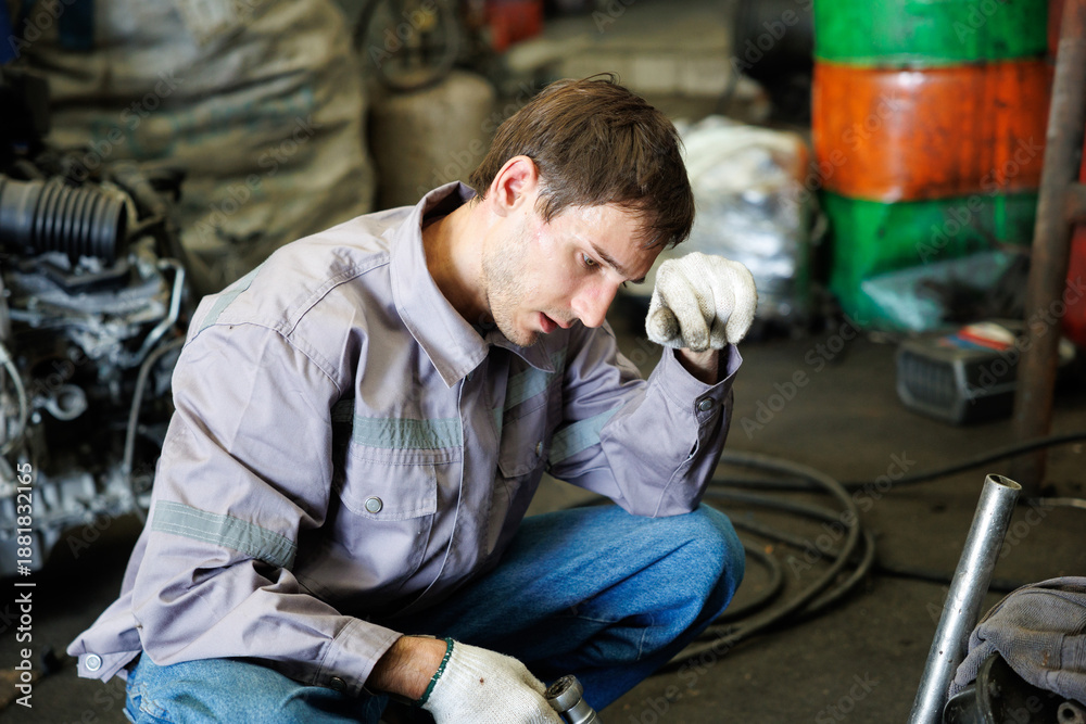Naklejka premium Worker feeling tired from hard work in a vehicle dismantling shop
