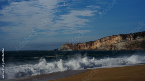 Wallpaper Mural Large ocean waves crashing on a sandy beach with a high cliff and fortress in the background, Nazare. Torontodigital.ca