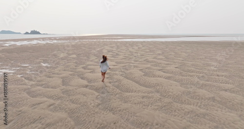 Bild auf Leinwand Woman running on Ko Lanta beach during low tide, finding freedom and vastness across rippled sand patterns extending towards the calm ocean and distant islands