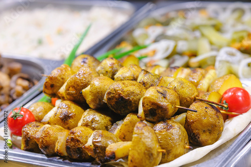 Fotografija Golden roasted potatoes on skewers with fresh red tomatoes at a hot food buffet