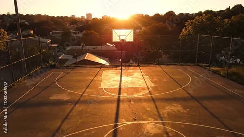 Basketball court at sunset with long shadows and worn surface on an outdoor urban rooftop