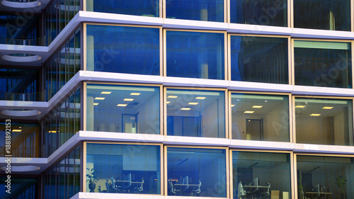 A modern tall building made of steel and glass, housing offices and financial institutions. Glass wall on the facade of the building.