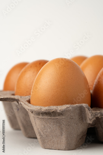 Cardboard egg carton containing fresh eggs on a clean white background.
