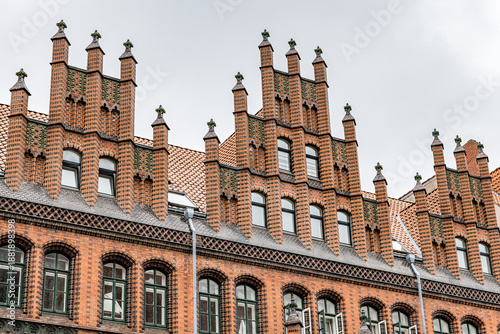 Wallpaper Mural A large brick building in Hanover Germany with a red roof and a clock tower. The building is empty and the sky is cloudy Torontodigital.ca