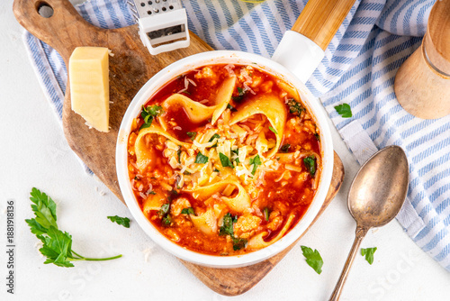 Warming comfort food, tasty chicken Lasagna Soup with tomato sauce, ground chicken meat fillet, grated cheese and wide lasagne pasta sheets