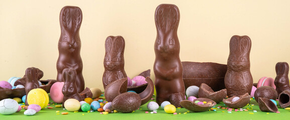 Easter egg hunting, sale and holiday traditions. Various candy and chocolate Easter eggs, bunny and rabbits on bright green background. Preparation for Easter, greeting card, Easter sale and shopping