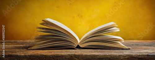 The Book Open on Rustic Wooden Table with Warm Yellow Background