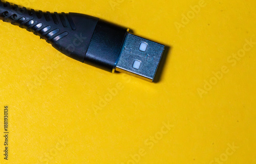 Black USB type-A cable connector on bright yellow background, close-up with copy space.