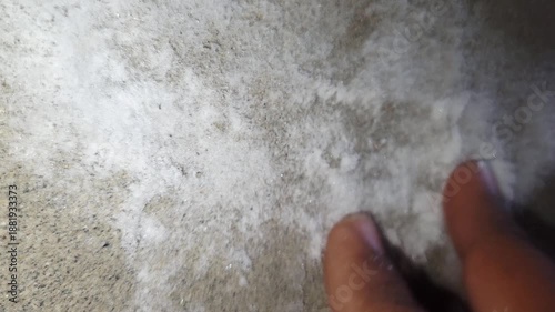 Hand cleaning white powdery efflorescence from a damp wall