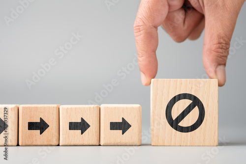 Φωτογραφία Human hand placing a wooden block with stop sign to block a workflow