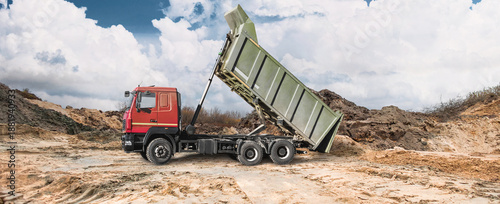 Obraz na plátně At the construction site, a dump truck can be seen dumping earth onto the site, creating earthen embankments, while the sky is overcast