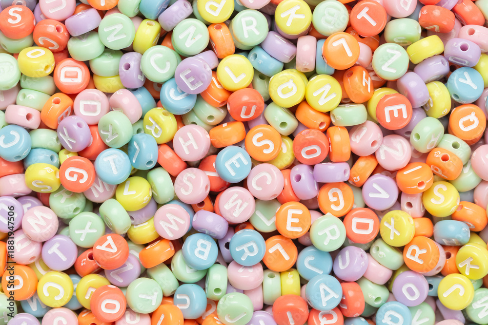 Fototapeta premium Pile of small round colorful english letters beads for background, Top view