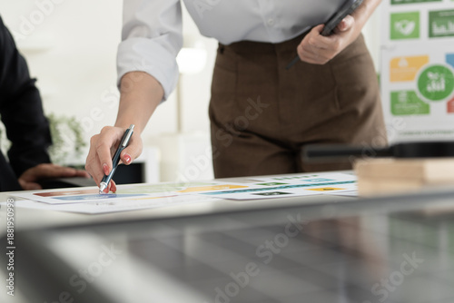 A diverse business team analyzing environmental charts and graphs in a collaborative meeting to create sustainable strategies in a modern office.