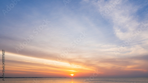 Sunset sky cloud sea water background in golden evening with orange, blue sun light,Horizon sea ocean sunrise sky landscape nature backgrounds warm gold sun down in golden hour summer season,Dusk sky