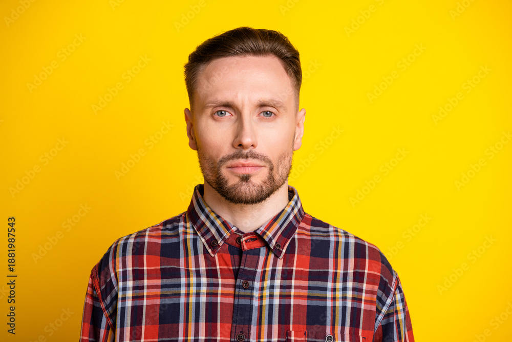 Obraz premium Young man in plaid shirt stands against bright yellow background for lifestyle fashion and advertising use
