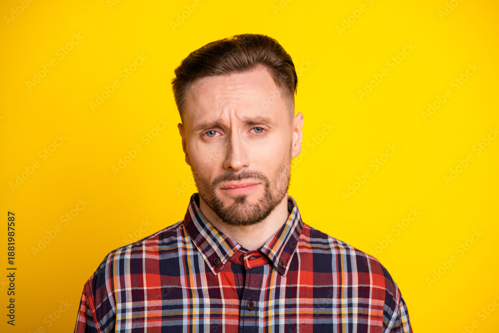 Obraz premium Young man in plaid shirt with thoughtful expression against bright yellow background for fashion lifestyle advertising