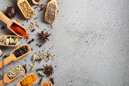 Foto Assorted Indian spices in wooden scoops scattered on a textured gray surface wit