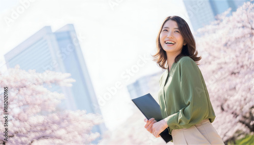 Obraz w ramie ビルと桜を背景にファイルを抱え微笑む女性