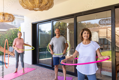 Cuadro en lienzo Senior woman with two friends practicing colorful hula-hoop exercise on pink mat