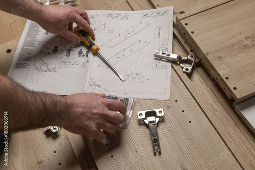 Photos Hands of a person assembling furniture with a screwdriver and instruction manual